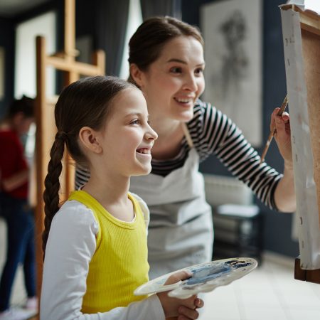 young girl painting with an instructor